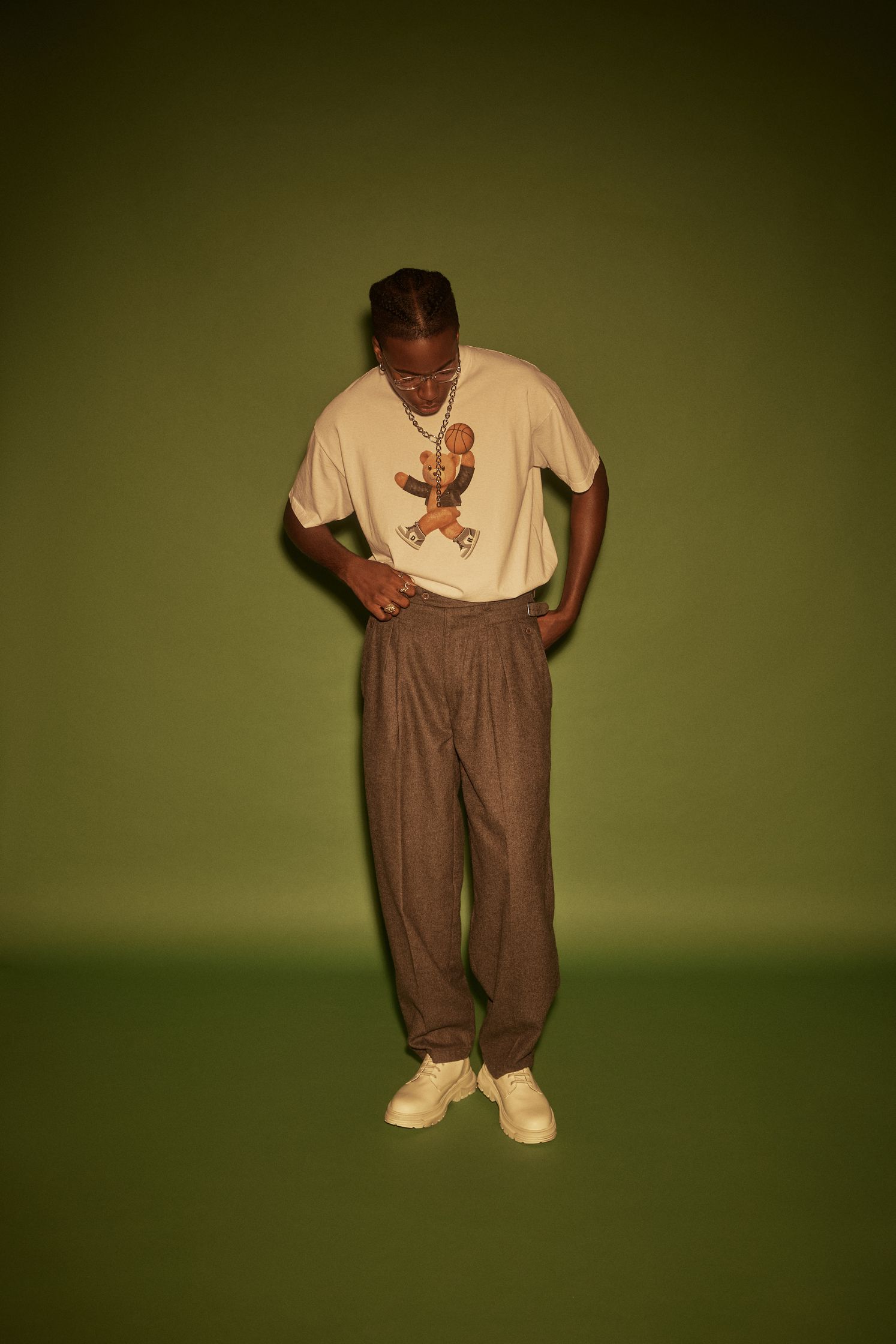 a man in a t - shirt and pants standing in front of a green background