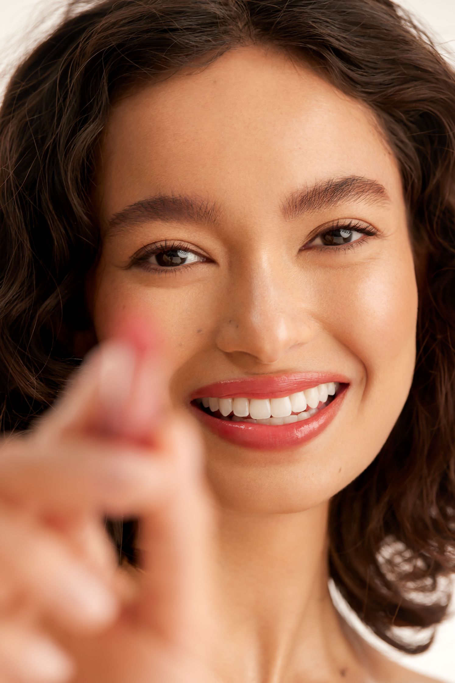 a woman is holding a lipstick and pointing to it