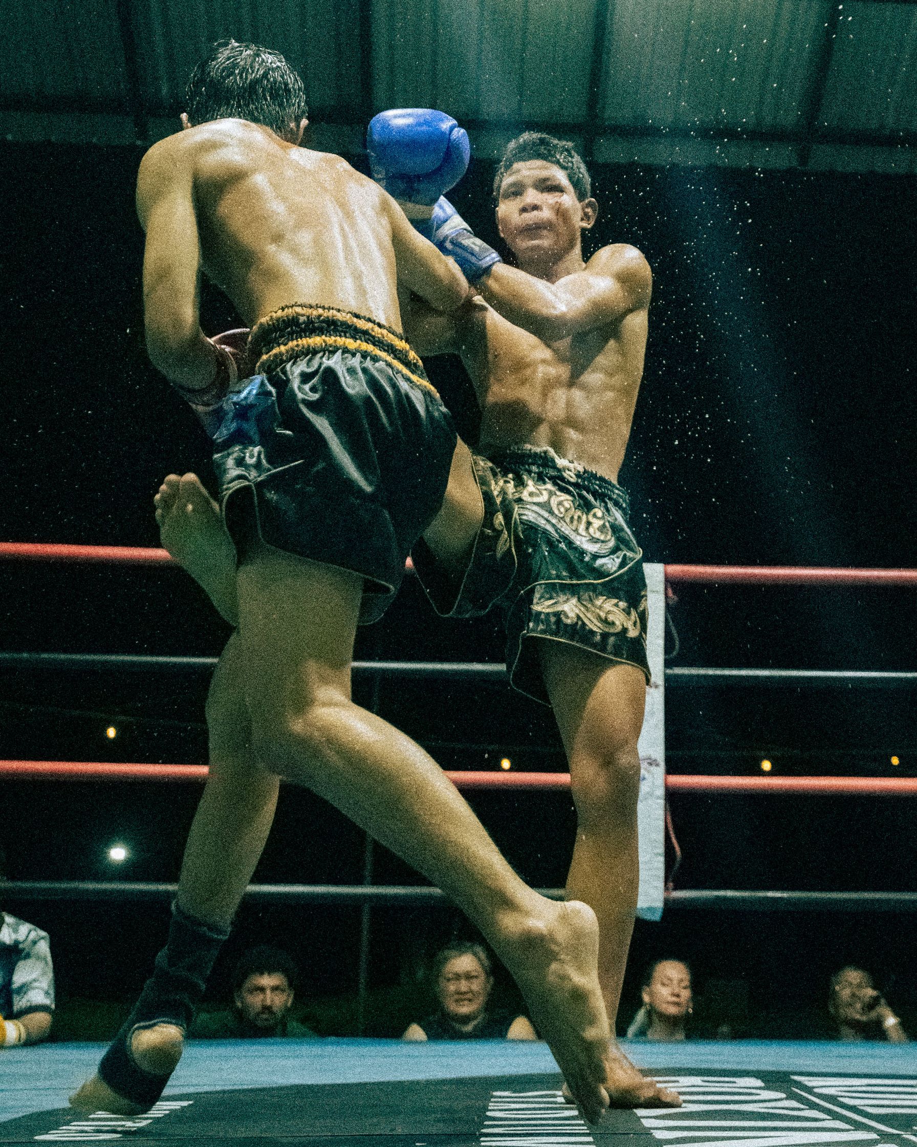 Action shot of a Muay Thai fighter landing a powerful middle kick on his opponent during a match in Koh Tao, Thailand.