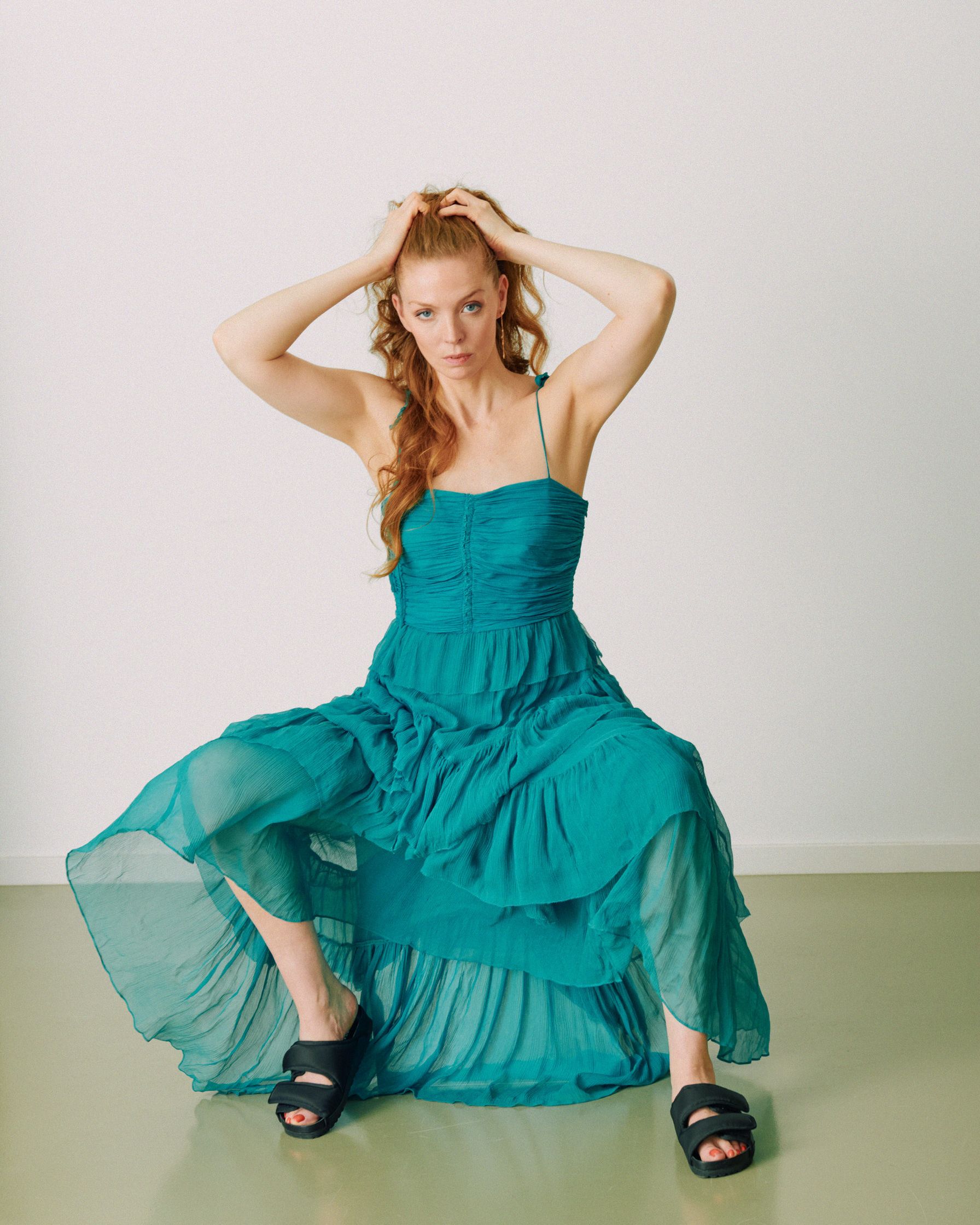 Pheline Roggan in a teal dress sitting on the floor
