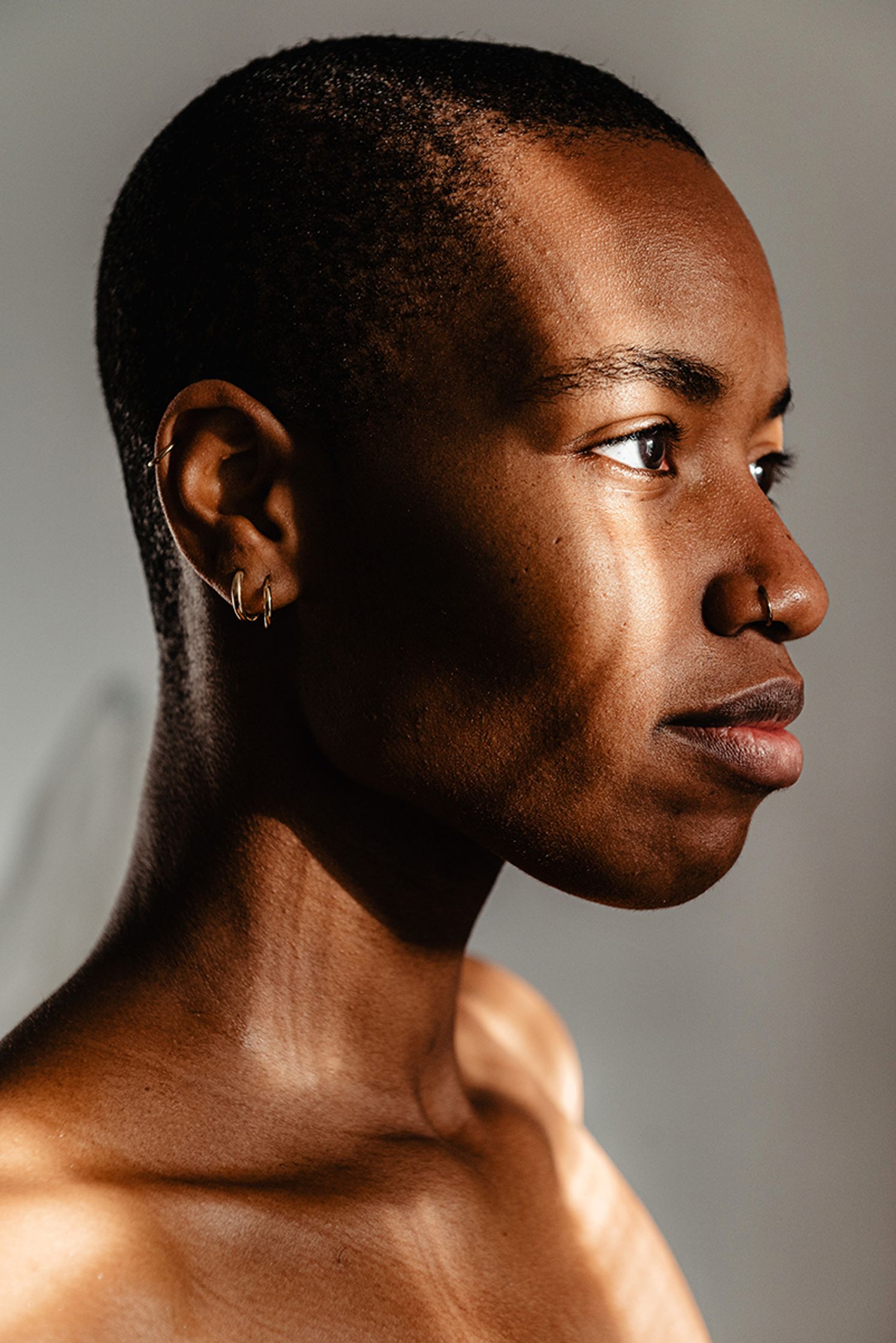 a portrait of a black woman with a shaved head and ear piercings