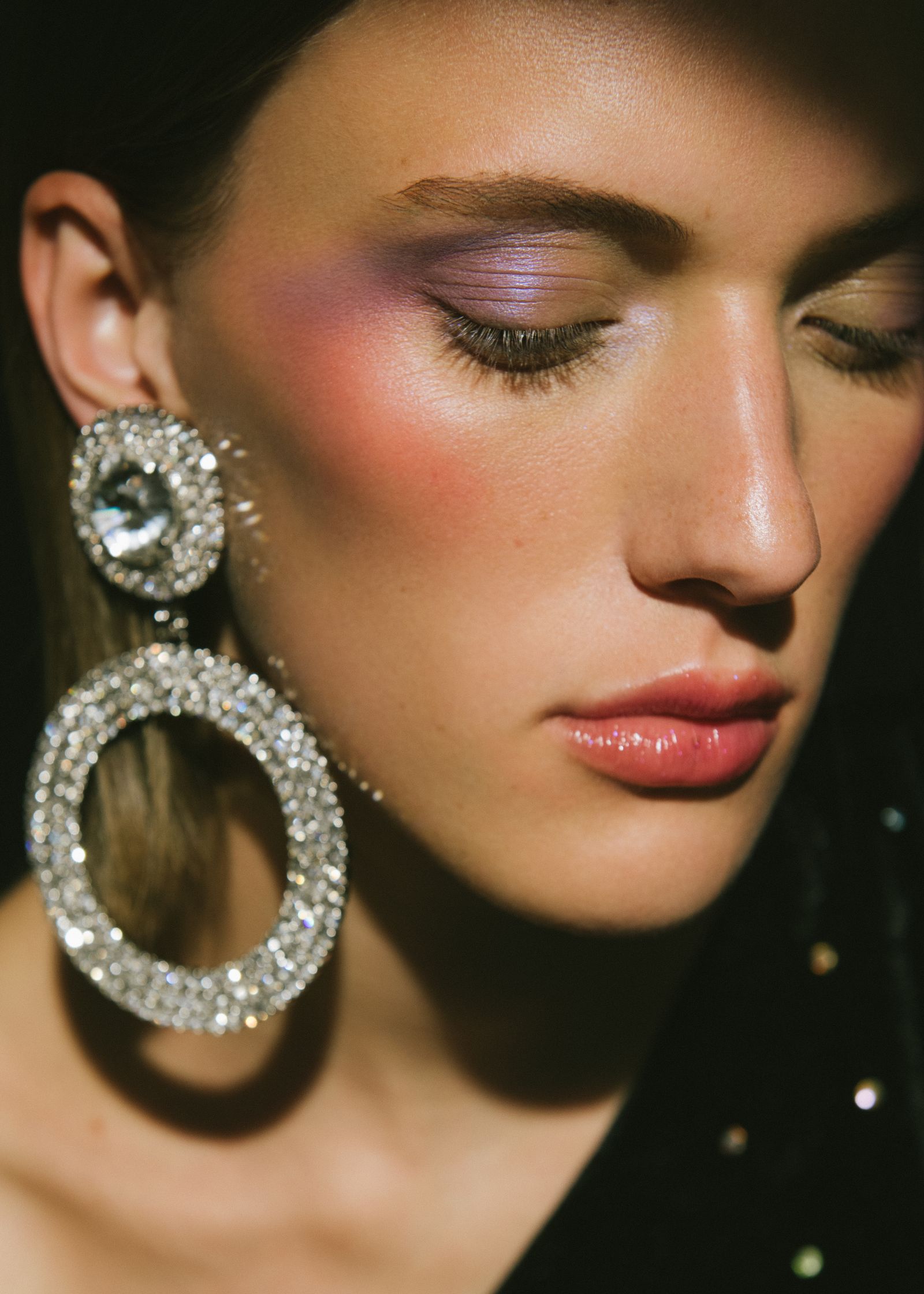 a woman wearing a pair of earrings with rhinestones