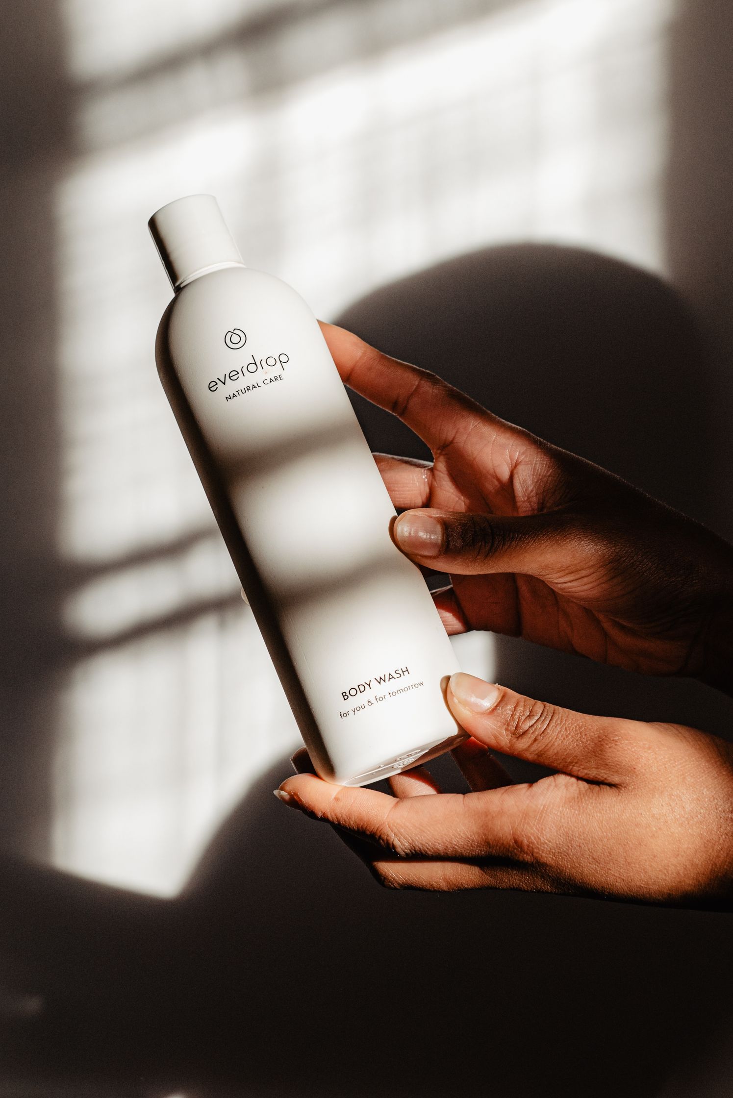 a woman's hand holding a bottle of everdrop body wash