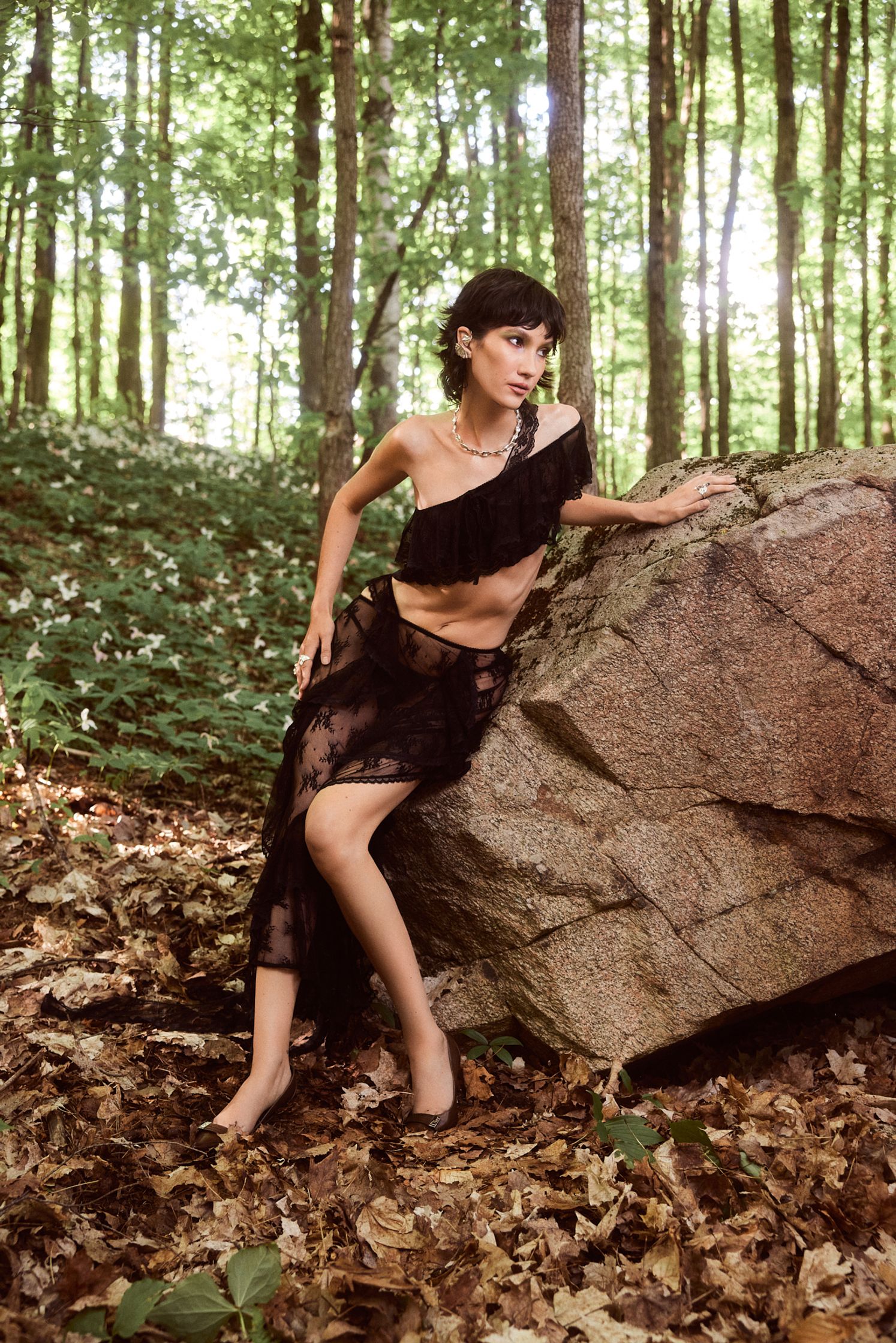 a woman sitting on a rock in the woods