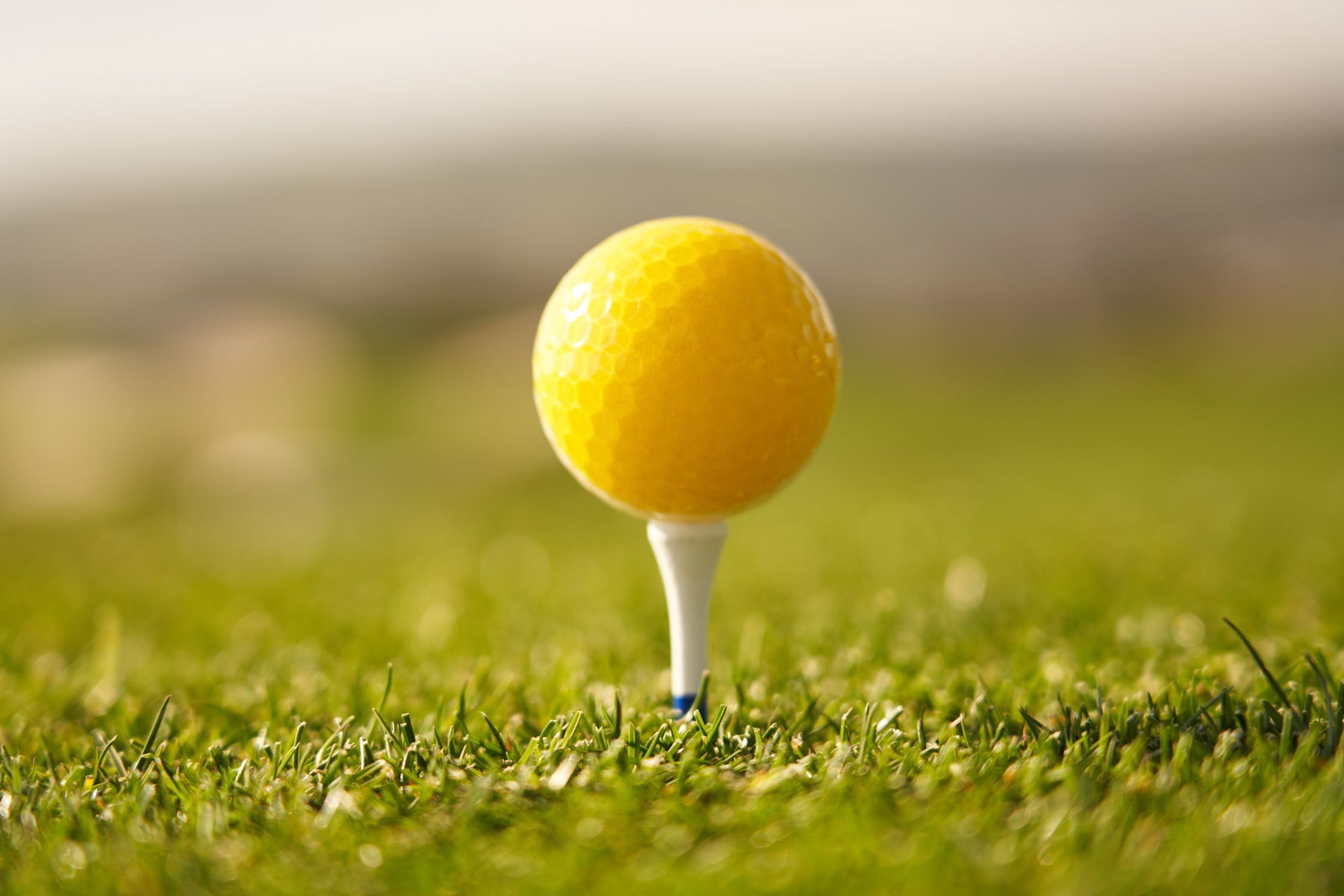 a yellow golf ball sits on top of a tee
