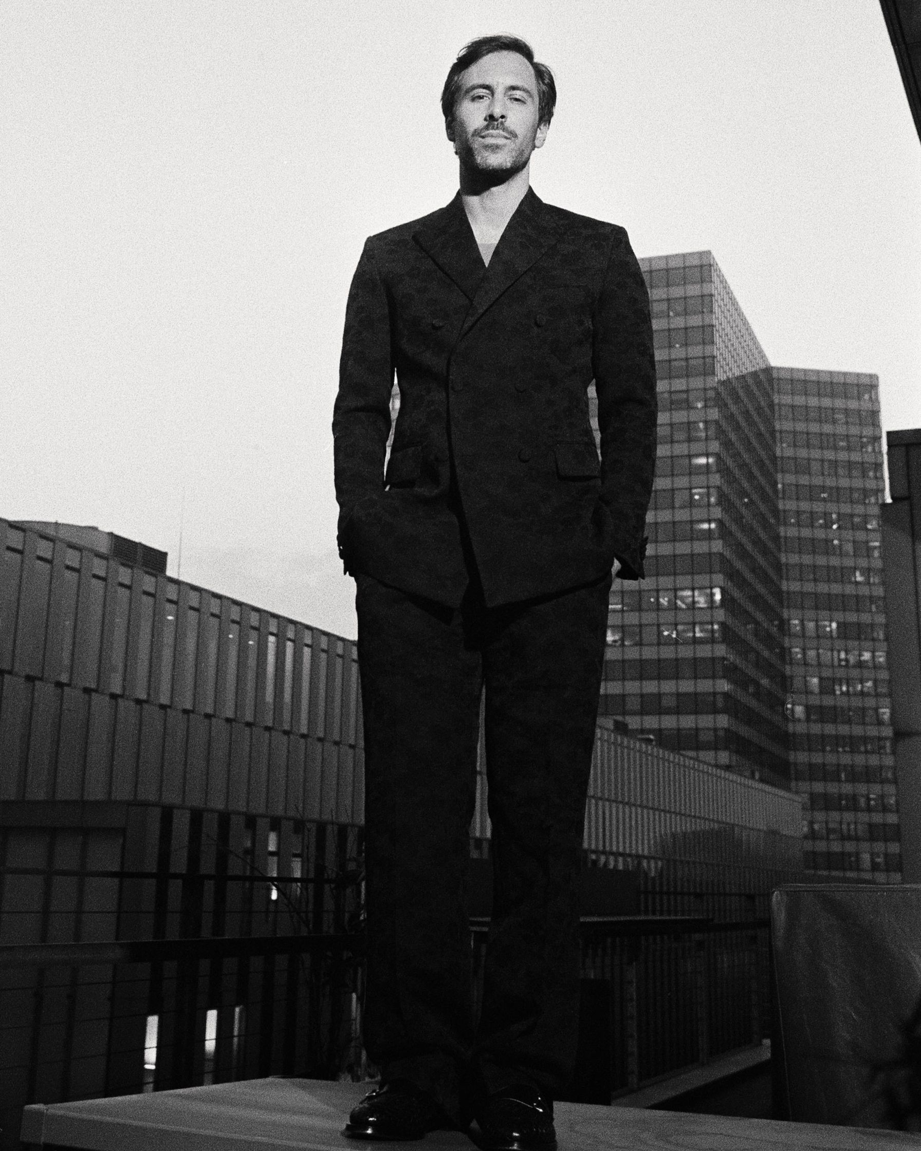 Max Giesinger in a suit standing on a rooftop