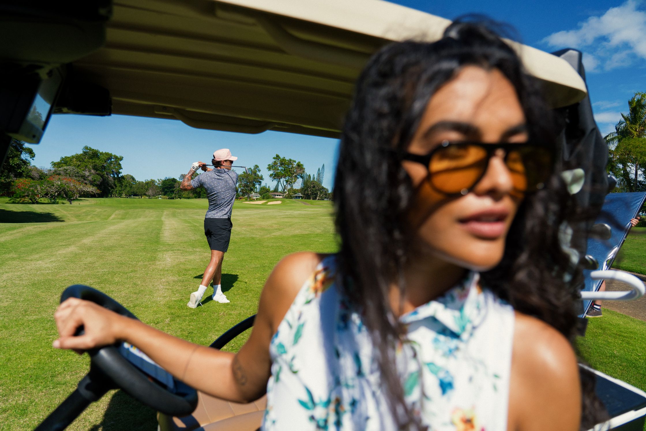 a woman is driving a golf cart on a golf course