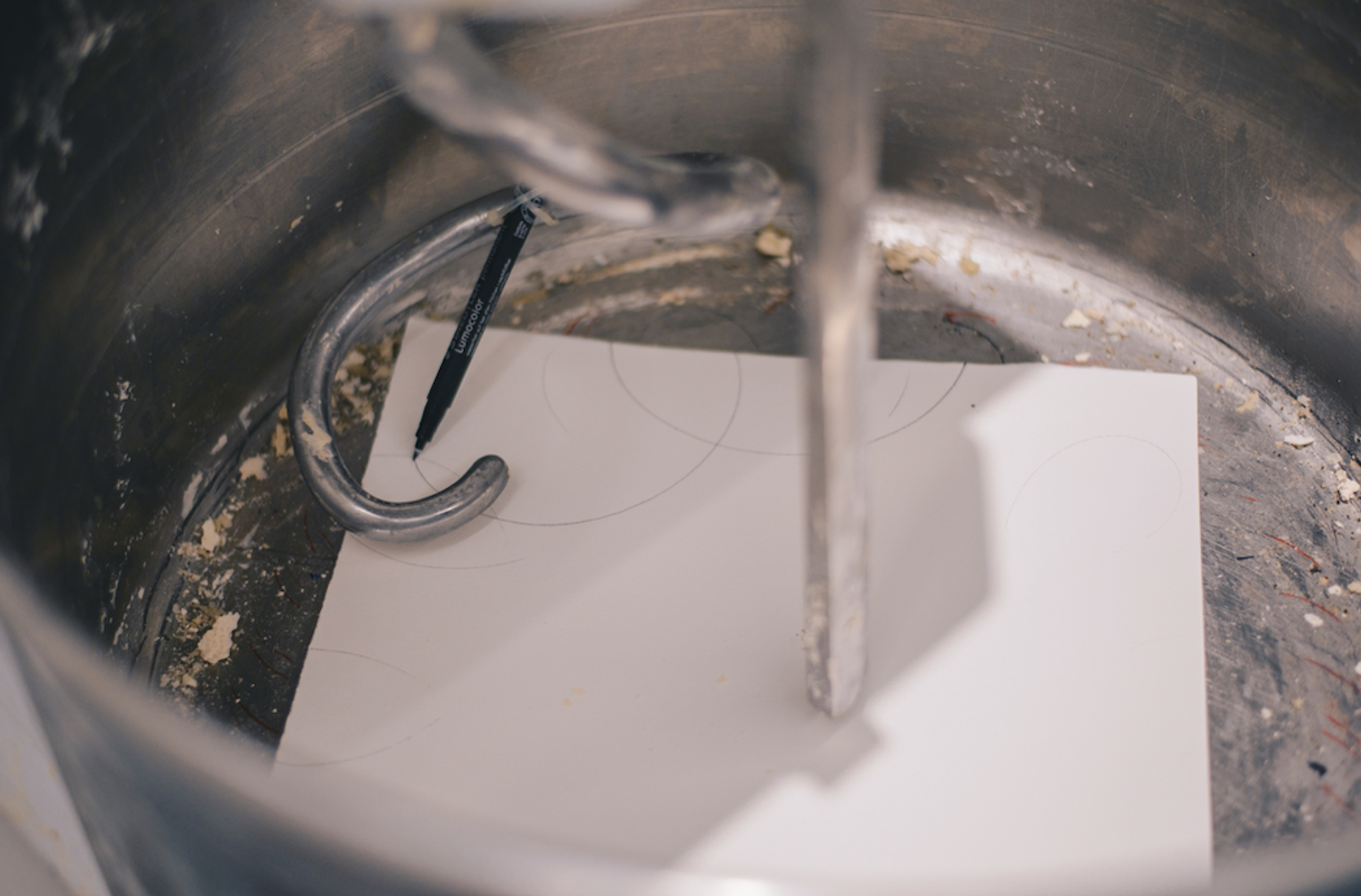 A black marker and a paper with circles drawn on it inside a dirty mixer.