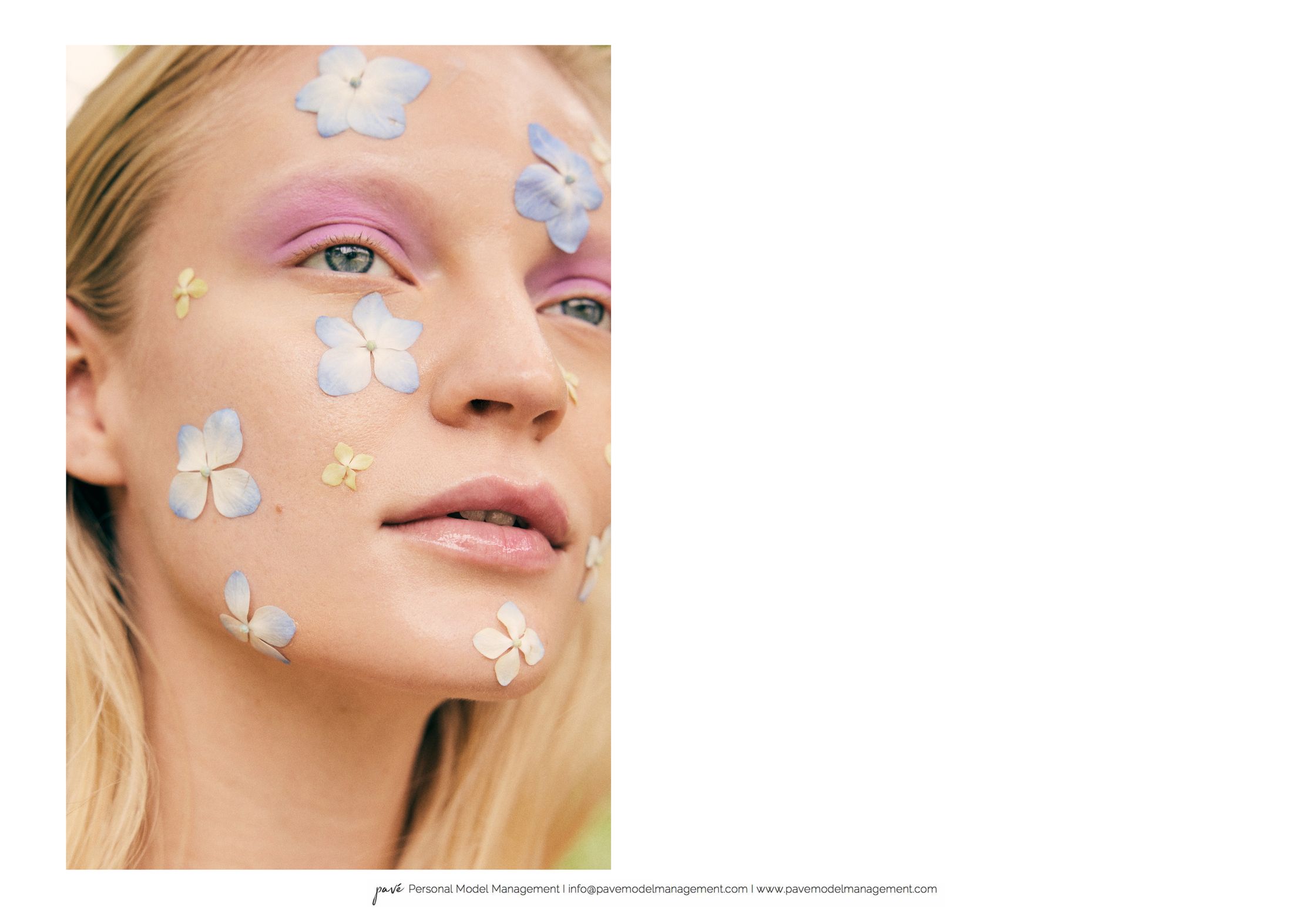 A woman with blonde hair, pink eyeshadow, and small purple and yellow petals on her face.