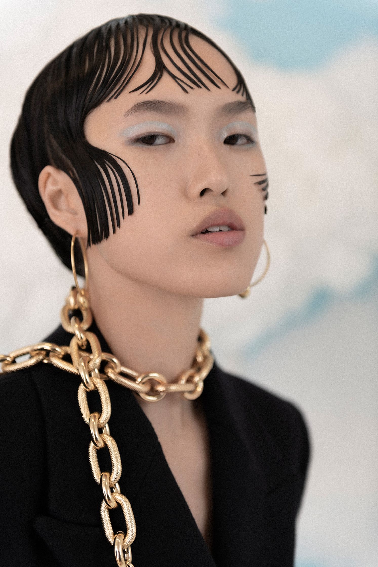 a woman wearing a black jacket and gold chains