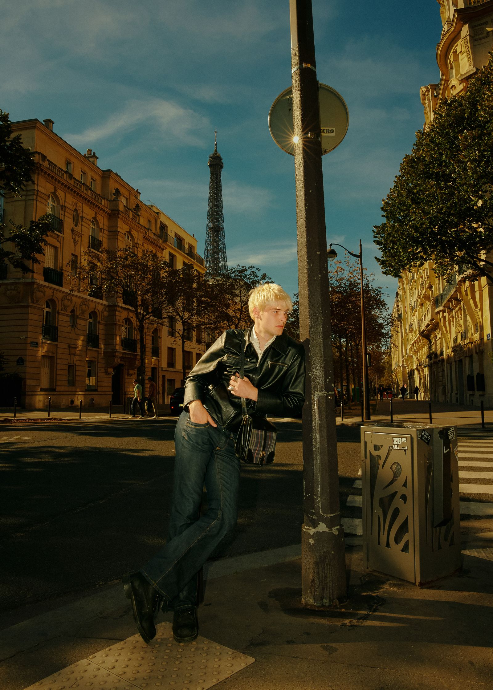 a man leaning against a pole with the eiffel tower behind him