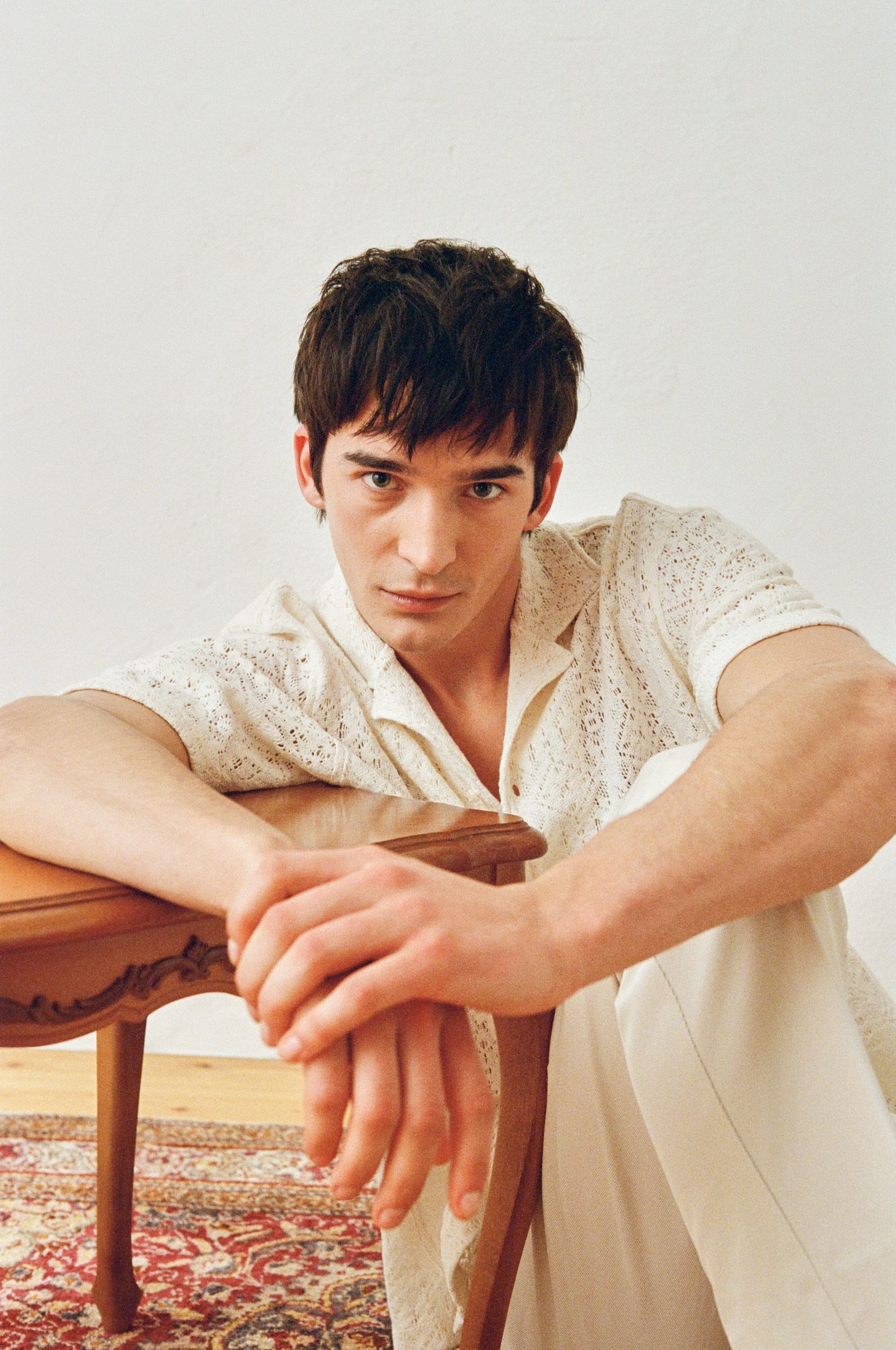 a young man leaning against a wooden table