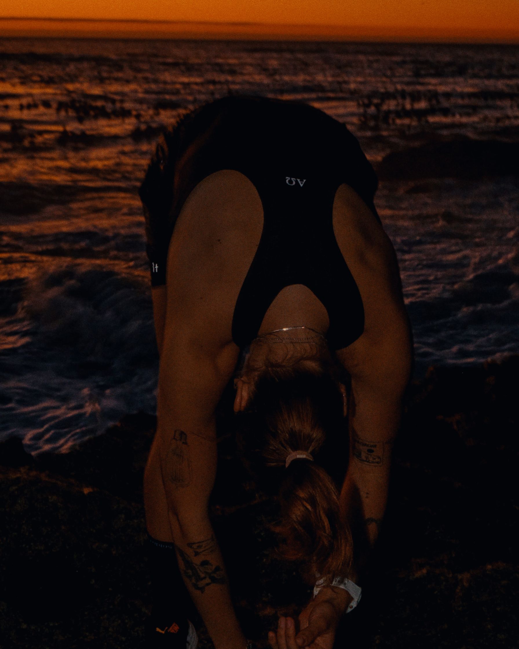 a woman wearing a black tank top tying her skateboard