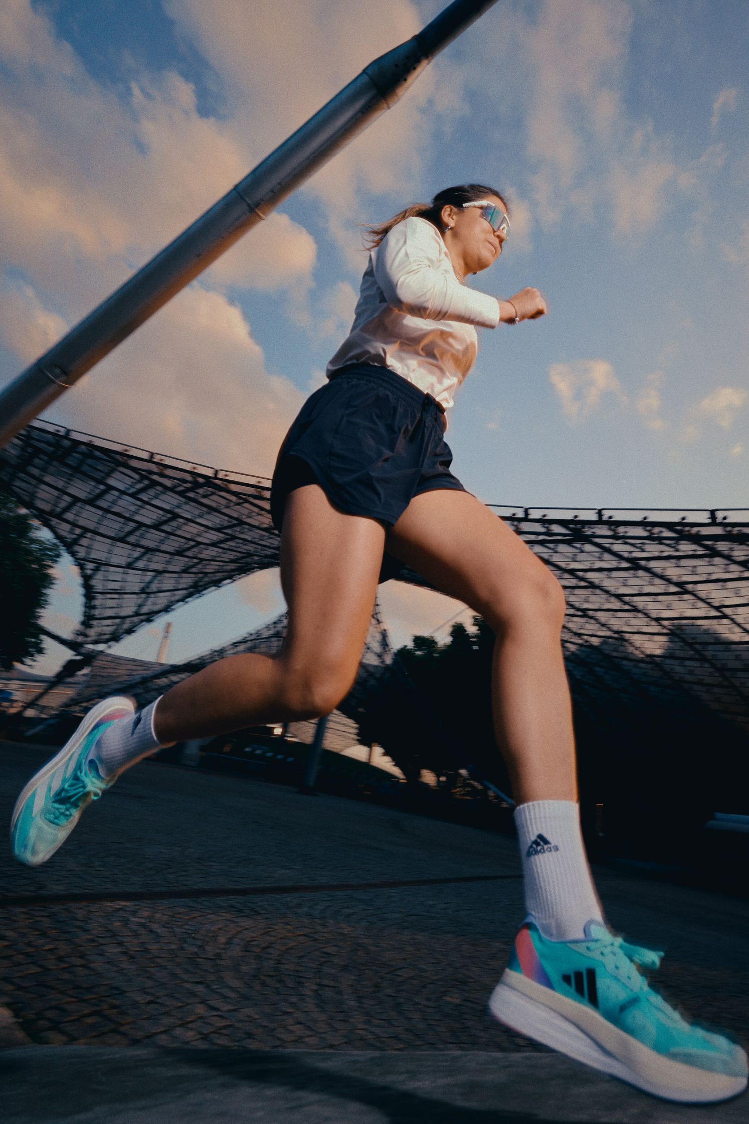 a woman is running on a track at sunset with Adidas shoes  by advertising photographer Martin Kula