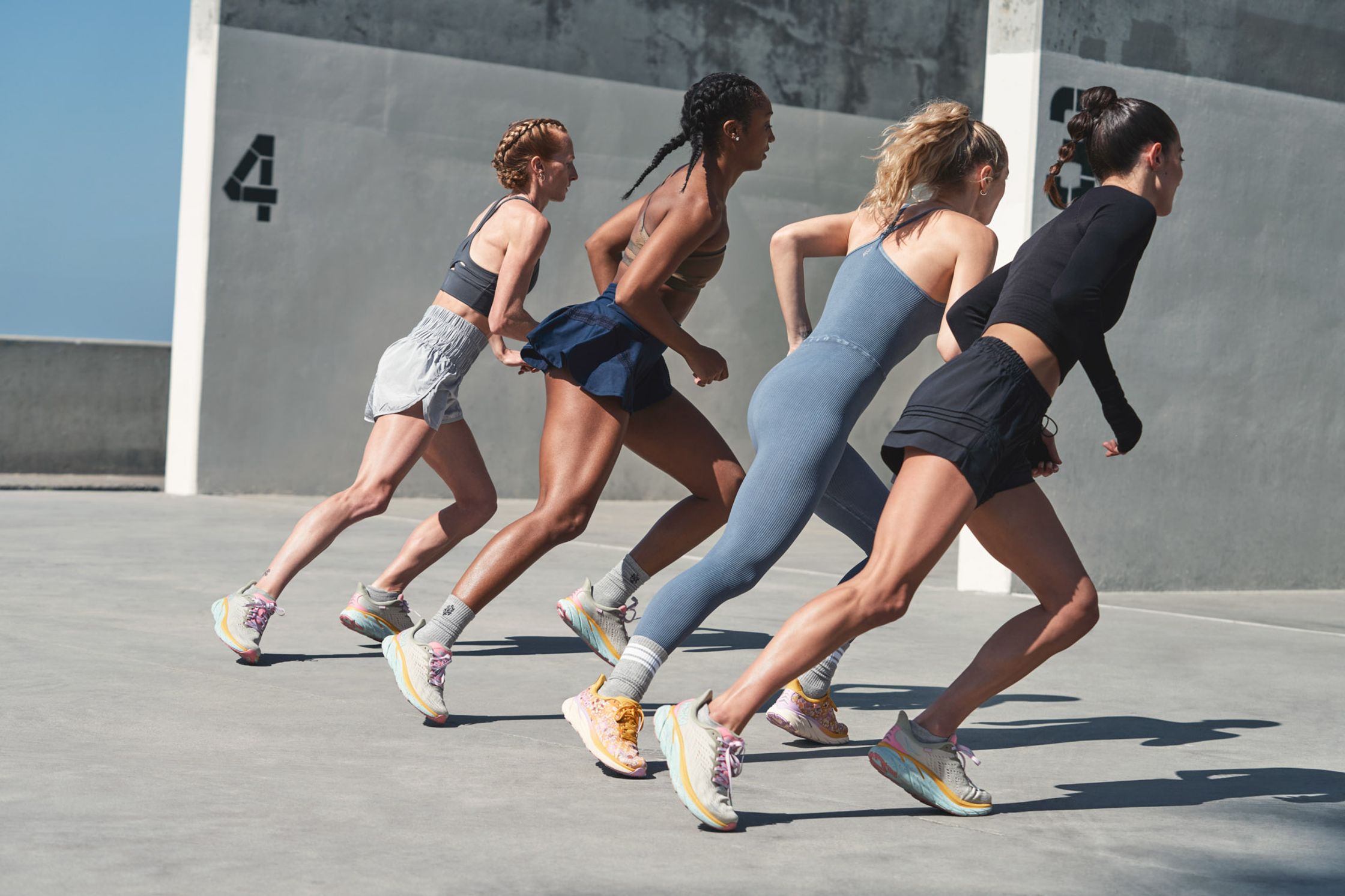a group of women running on a concrete wall