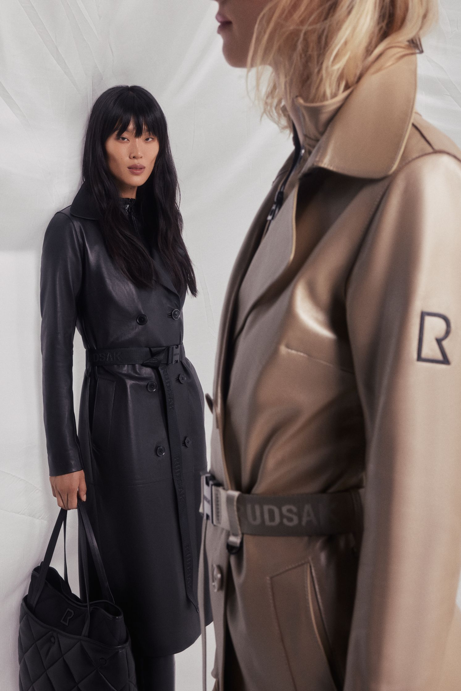 two women are standing next to each other in a trench coat