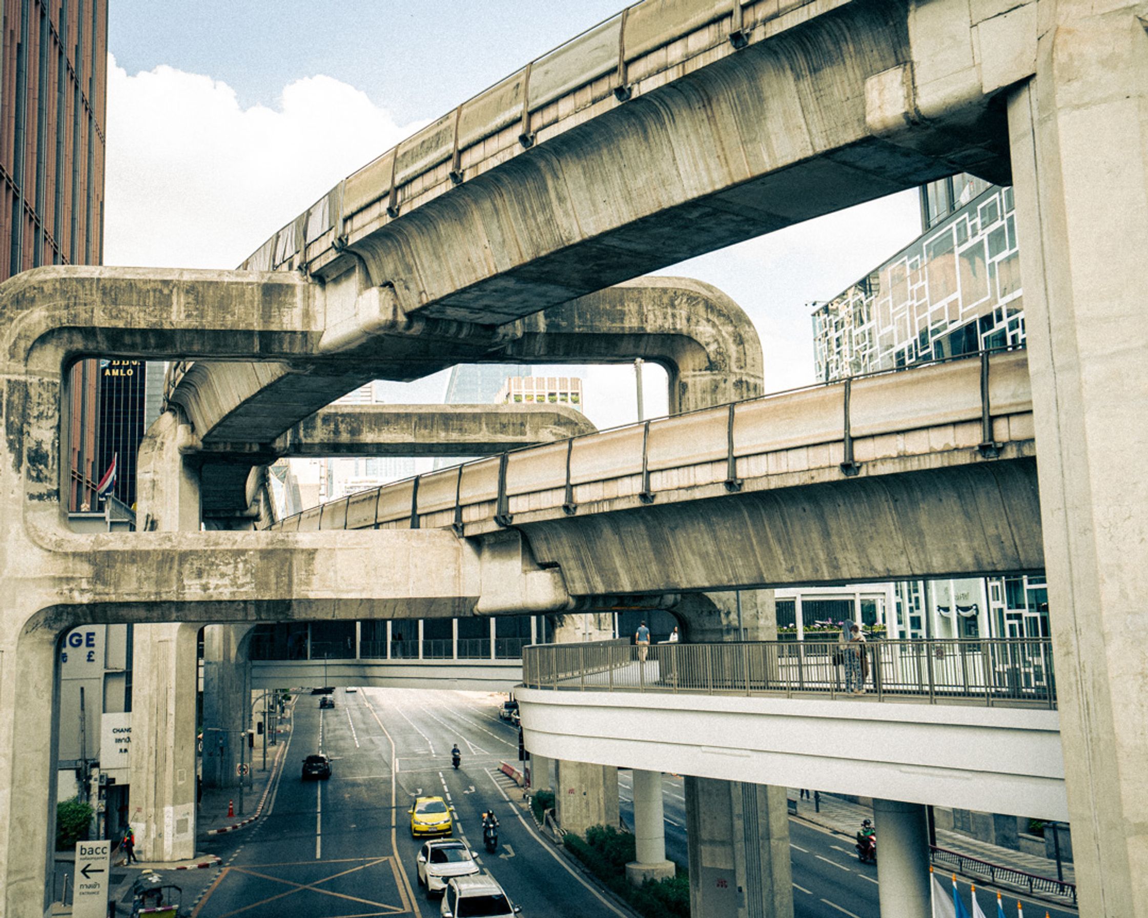 An elevated shot showing complex intersecting highways in Bangkok, Thailand. A minimalist and graphic urban landscape study of traffic flow and concrete architecture.
