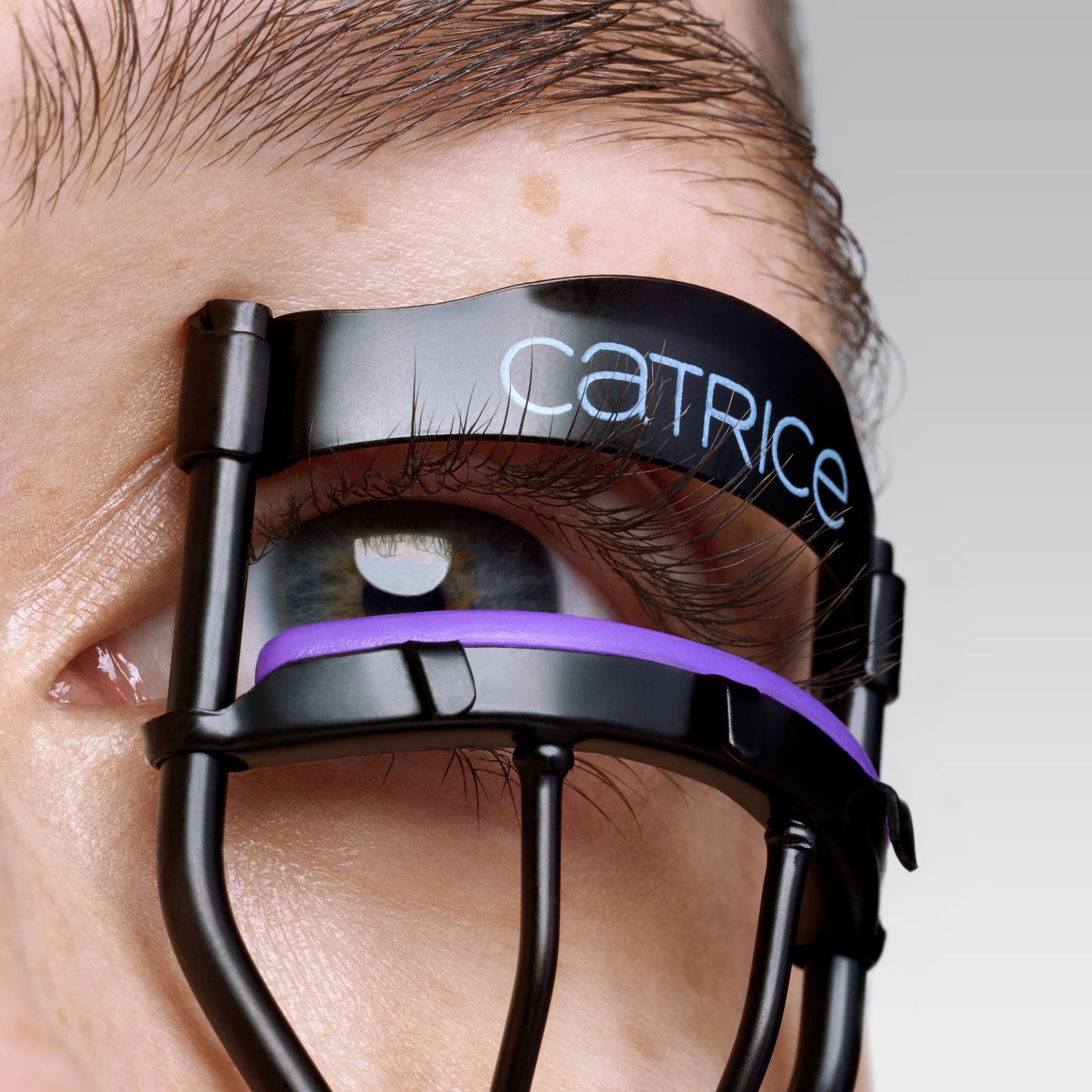 a woman's eye with an eyelash curler attached to it
