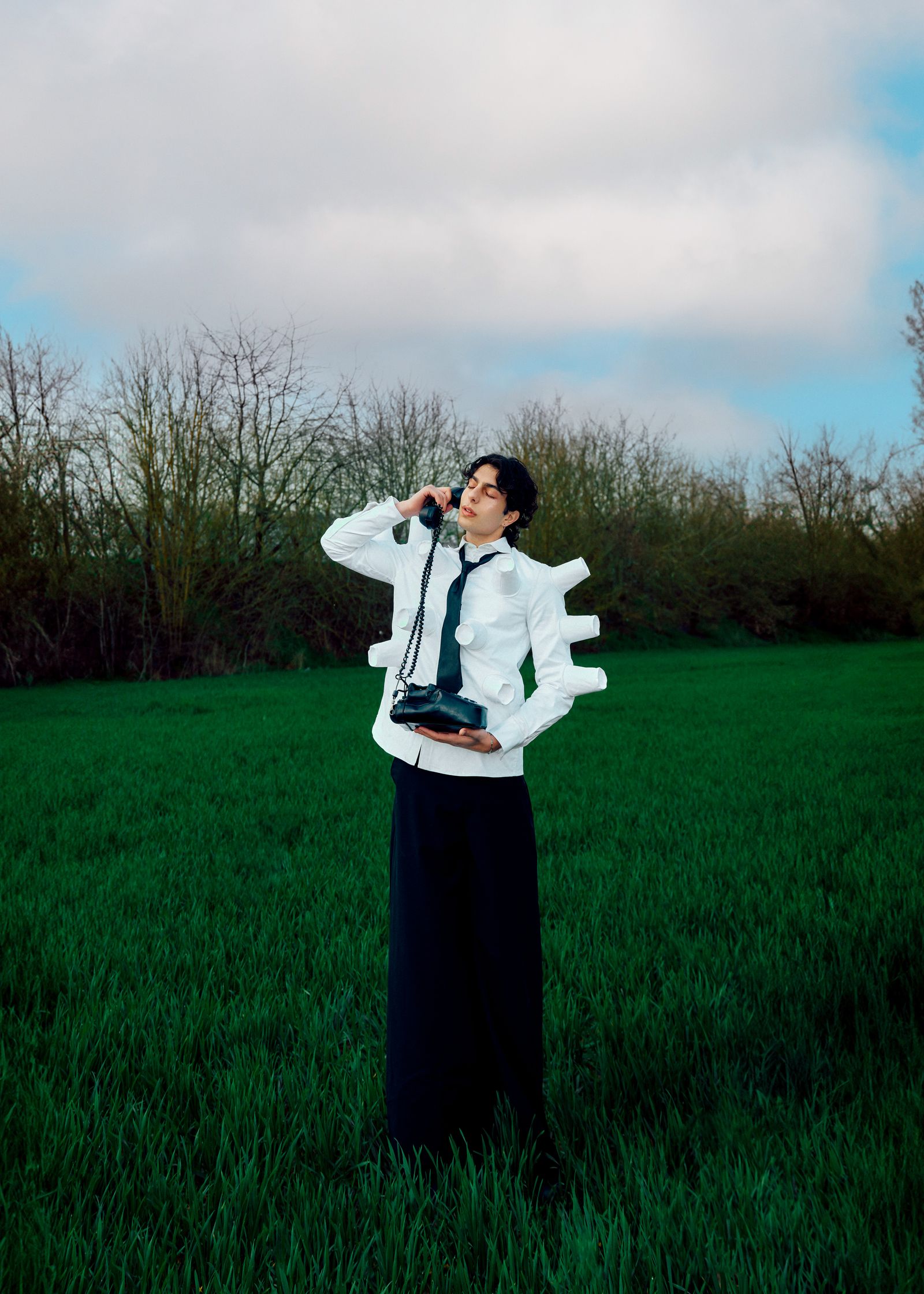 a man standing in a field holding a phone