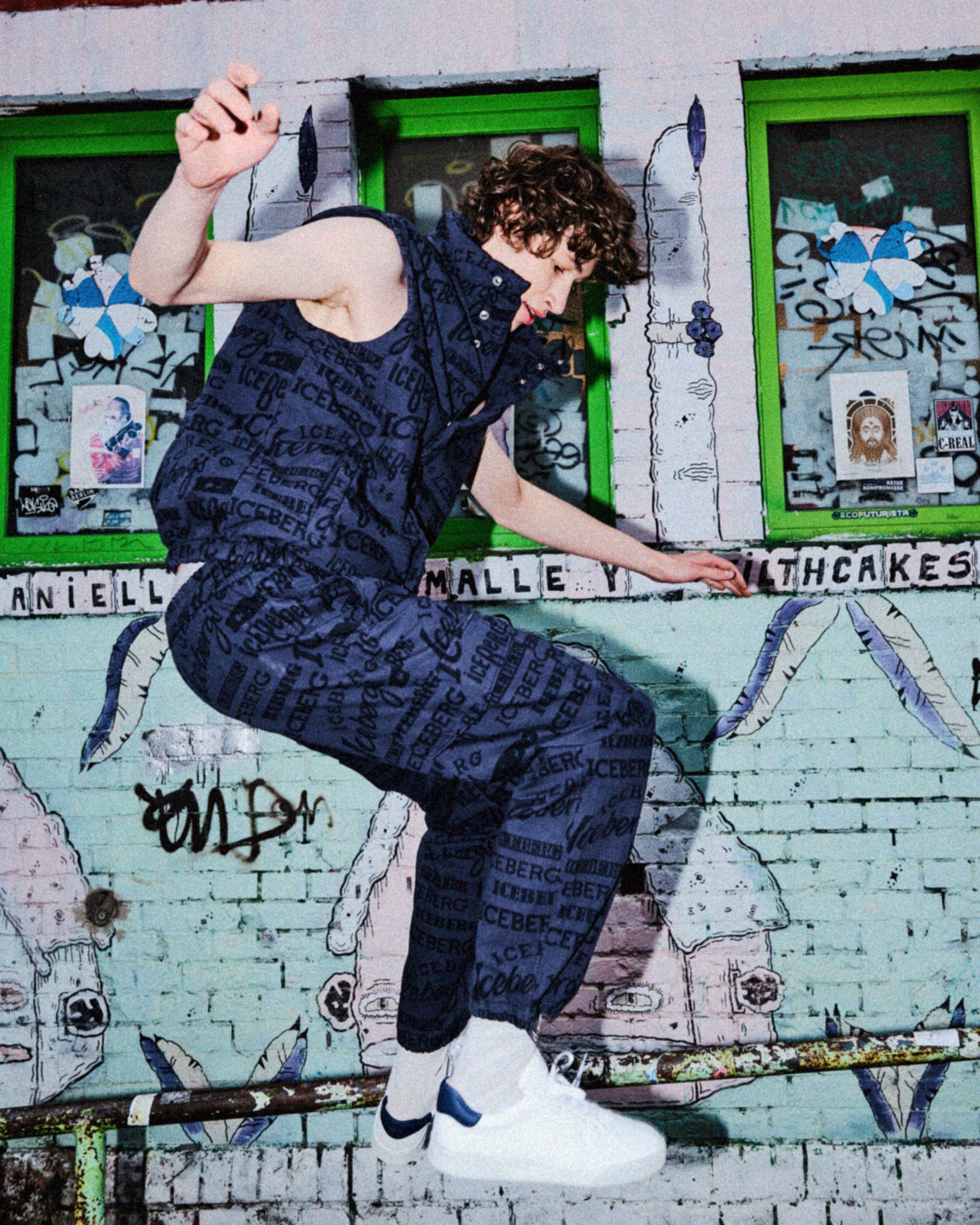 a young man is jumping in front of a graffiti wall