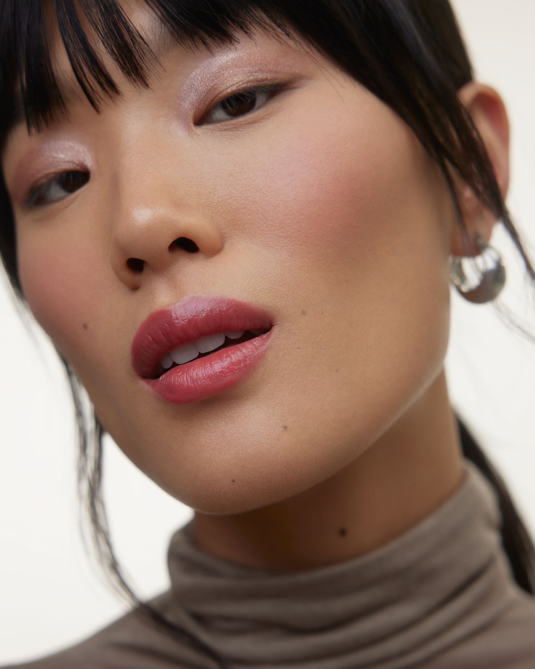 a woman wearing a turtle neck and pink lipstick