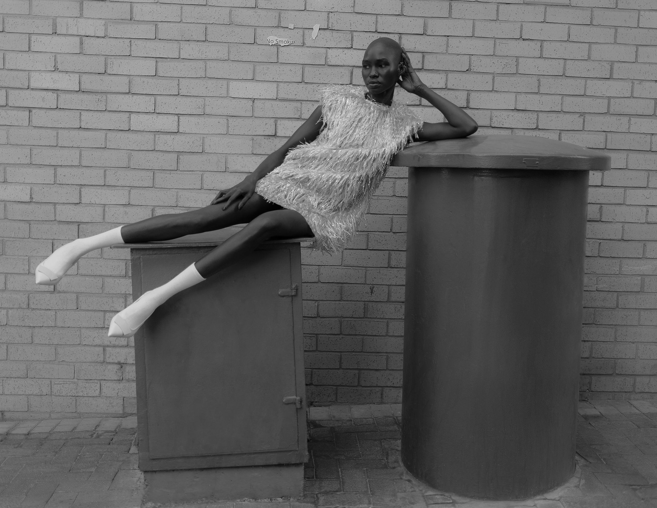 a black and white photo of a woman posing on top of a trash can