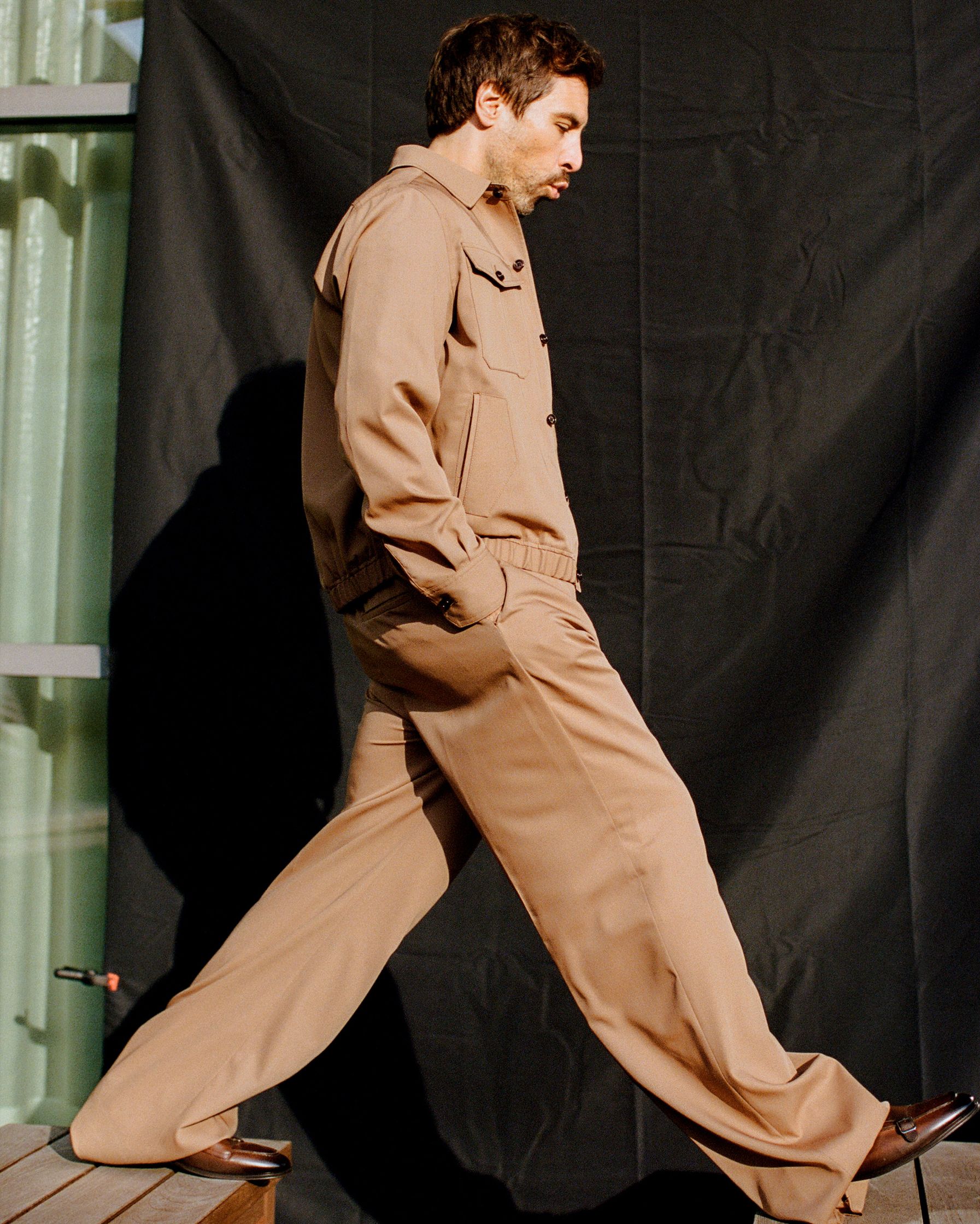 Max Giesinger in a tan suit walking on a wooden deck