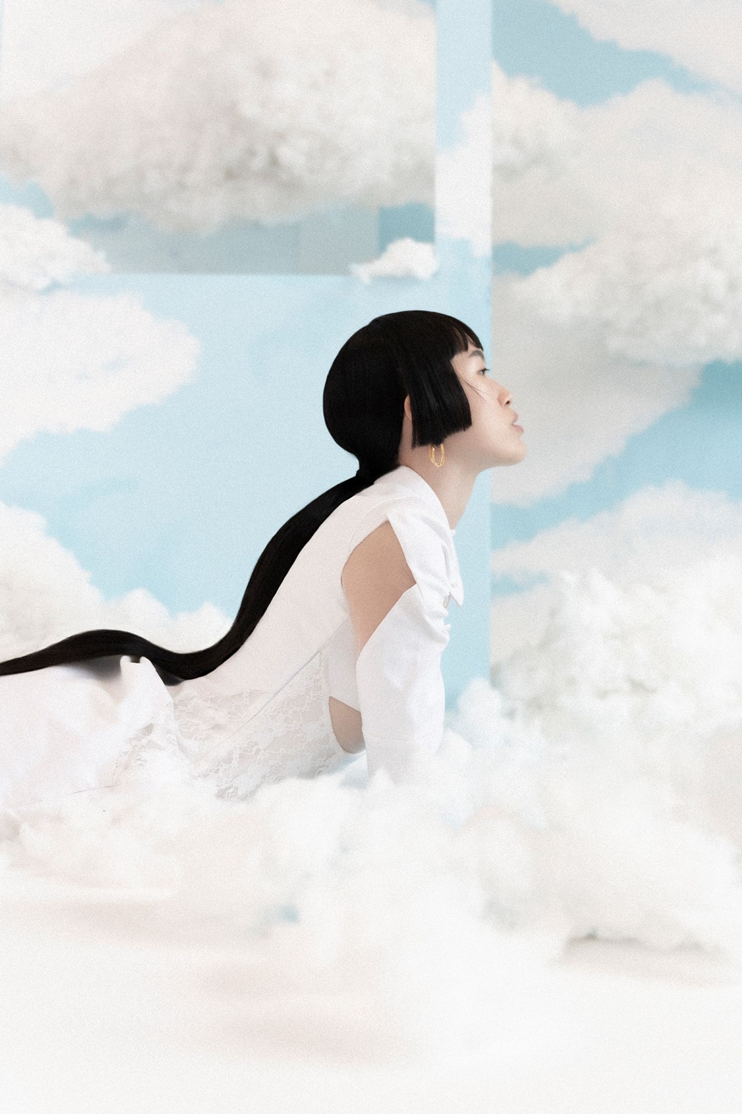 a woman laying on a cloud in a white dress