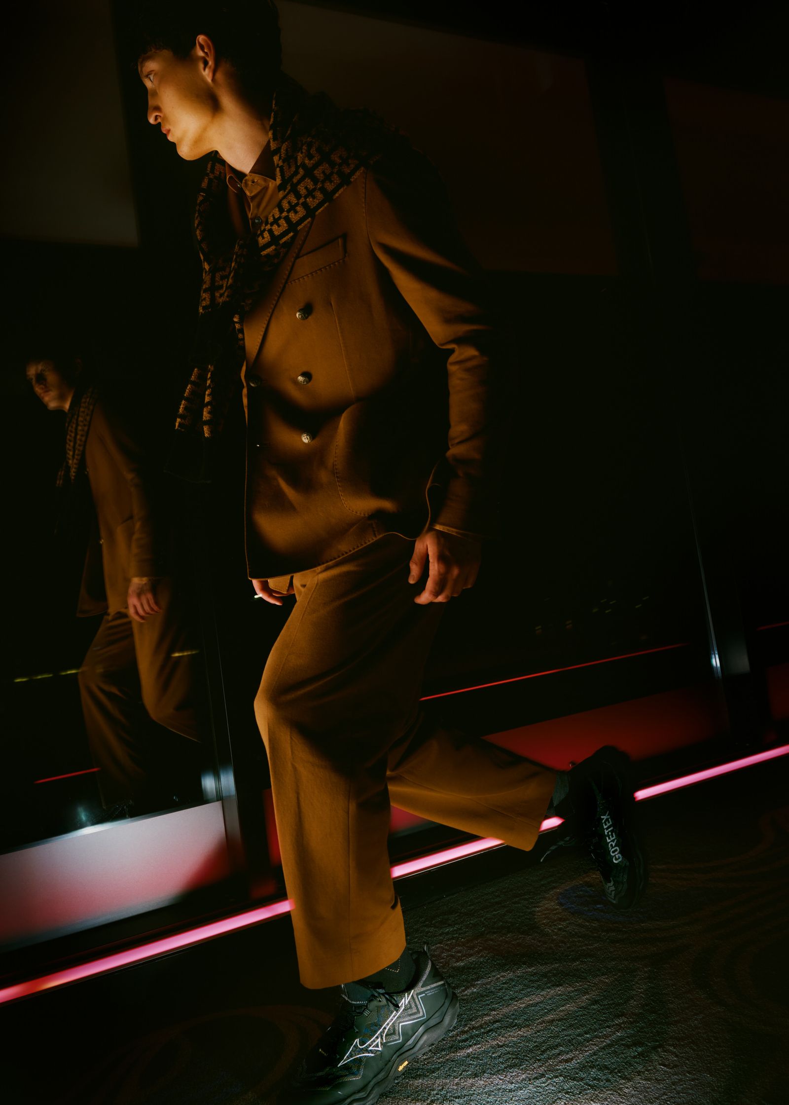 a man in a brown suit walking in a dark room