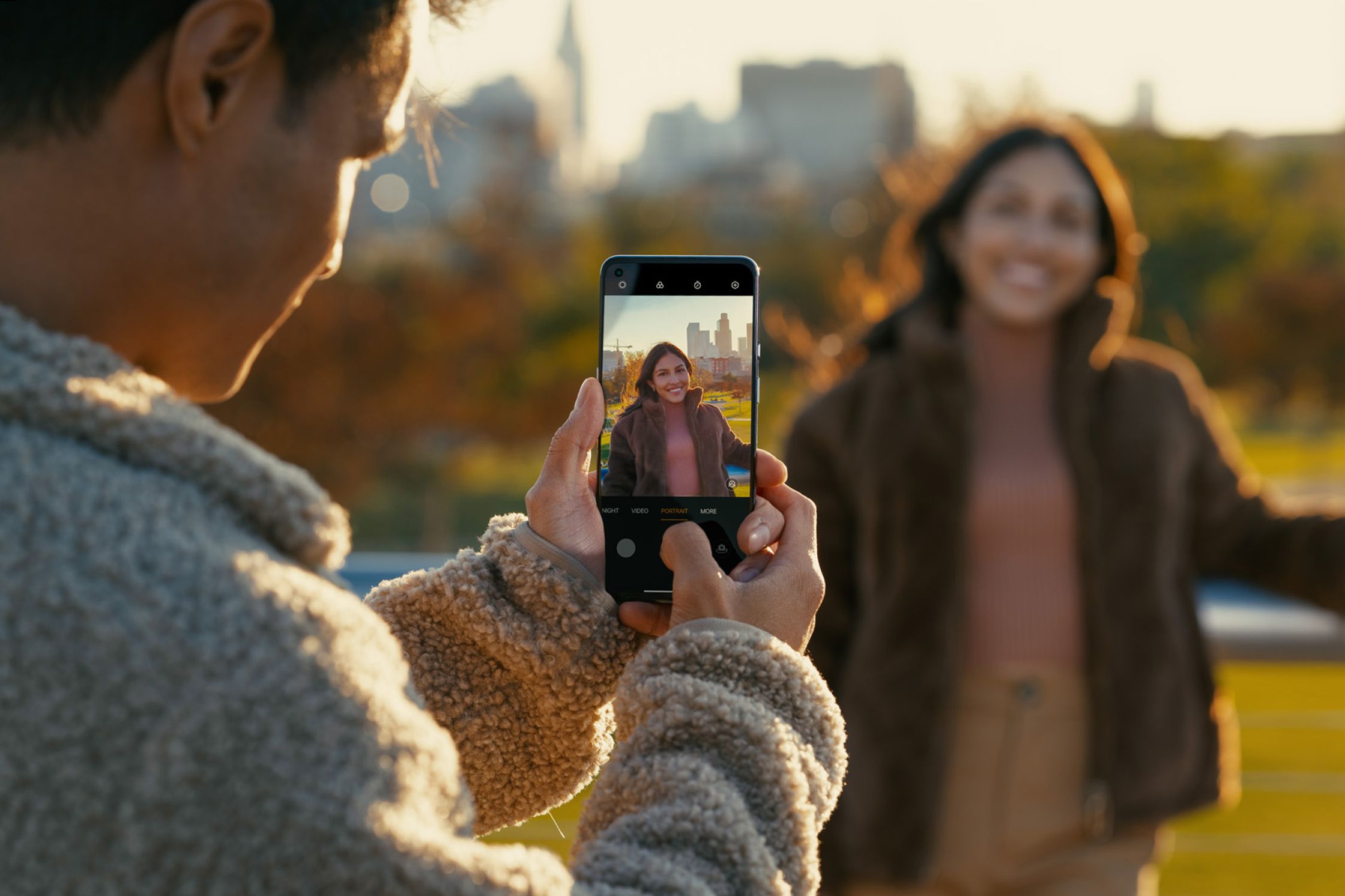 a man is taking a picture of a woman in front of a city