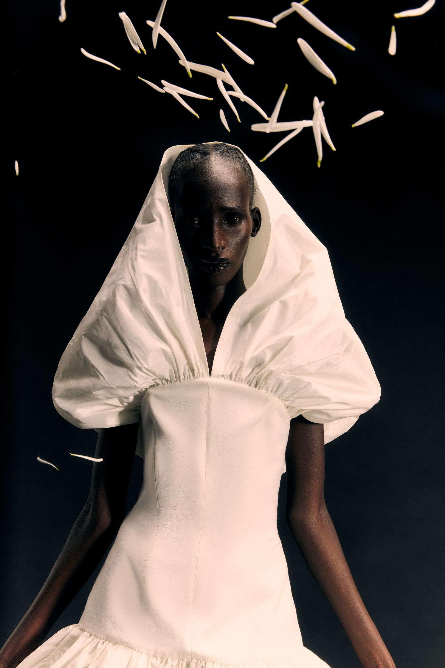 a woman in a white dress with feathers flying around her