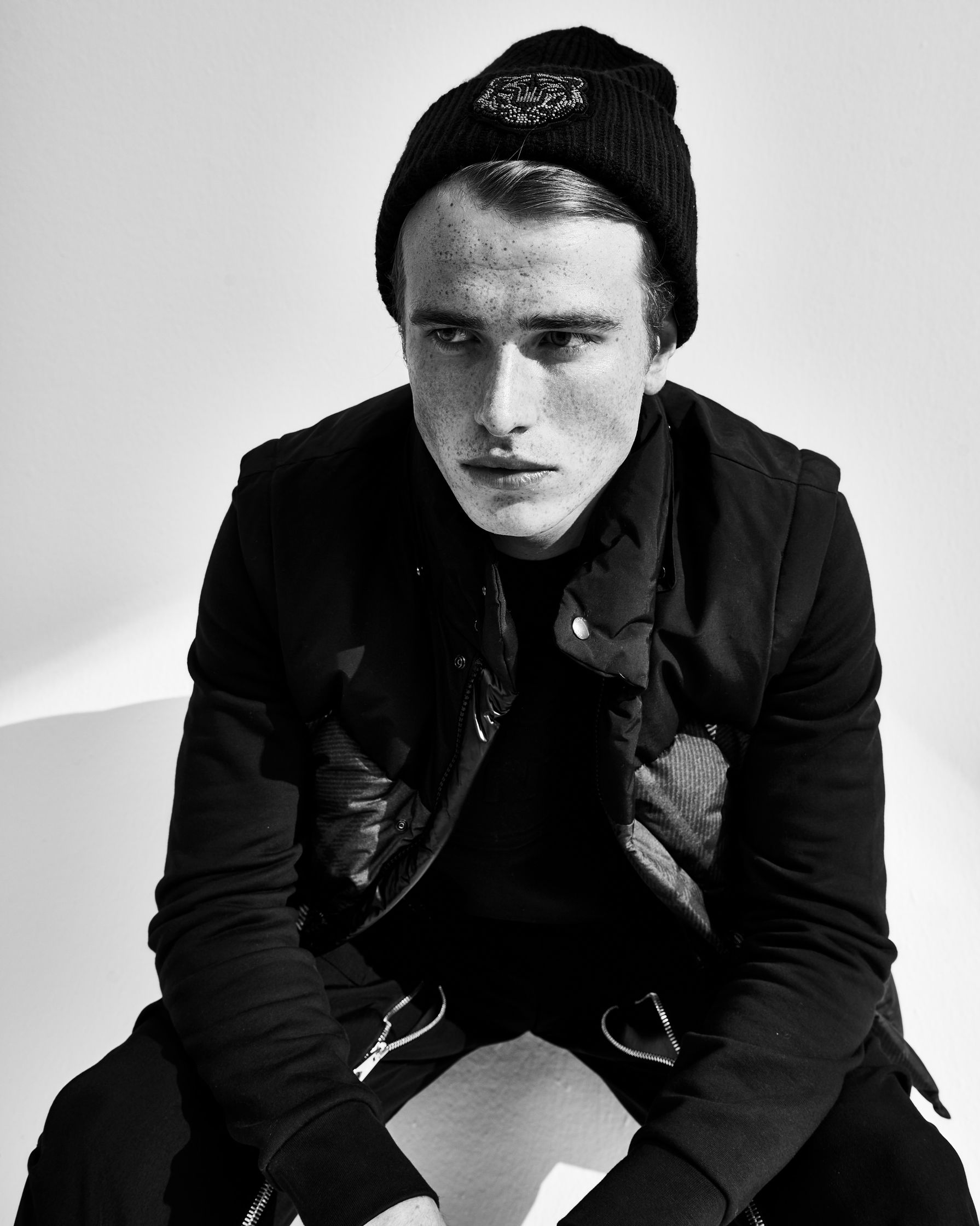 a black and white photo of a young man wearing a beanie