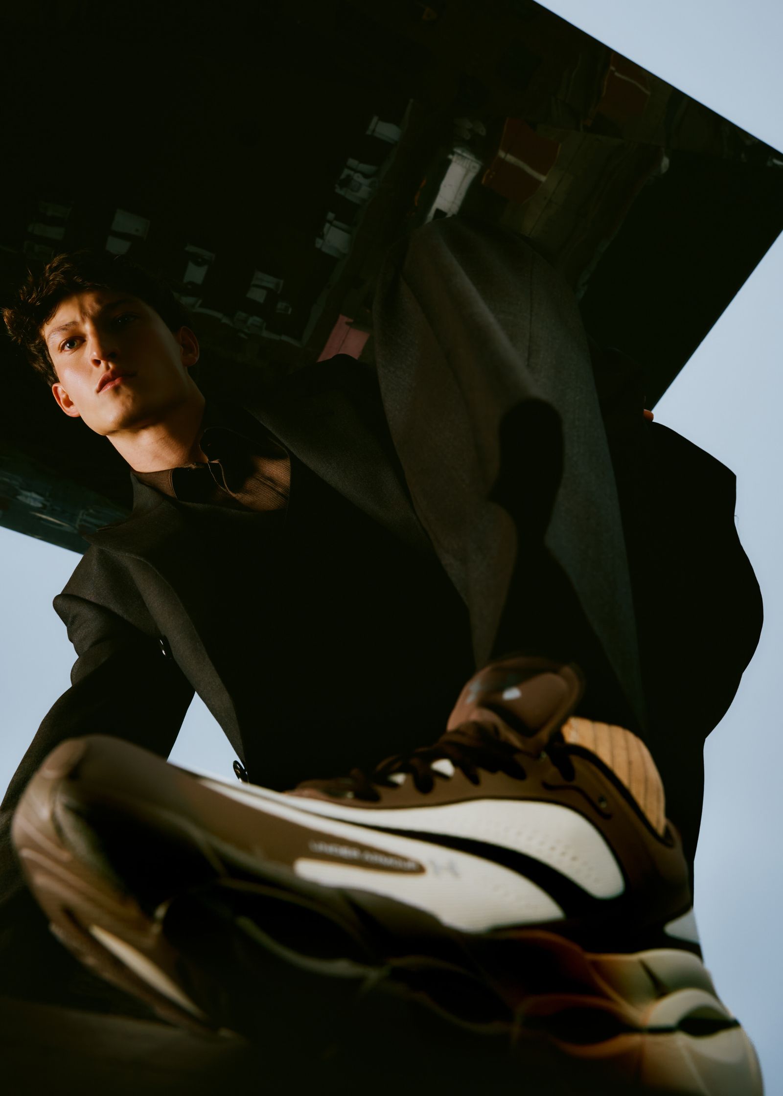 a man in a suit leaning over a pair of sneakers