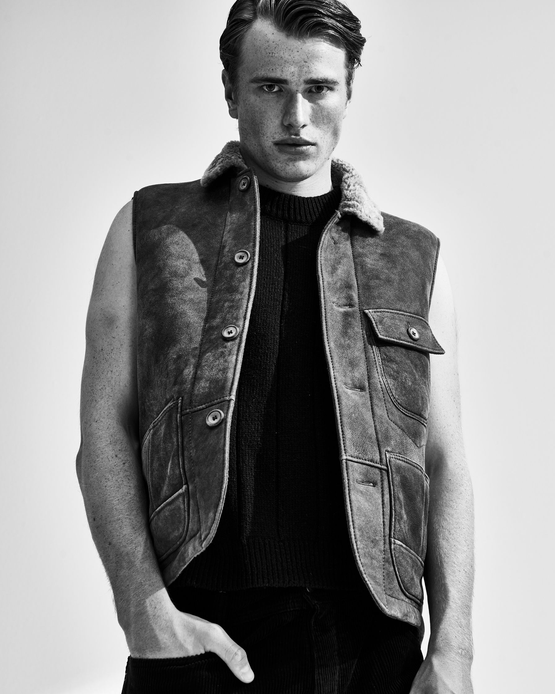 a black and white photo of a man in a leather vest