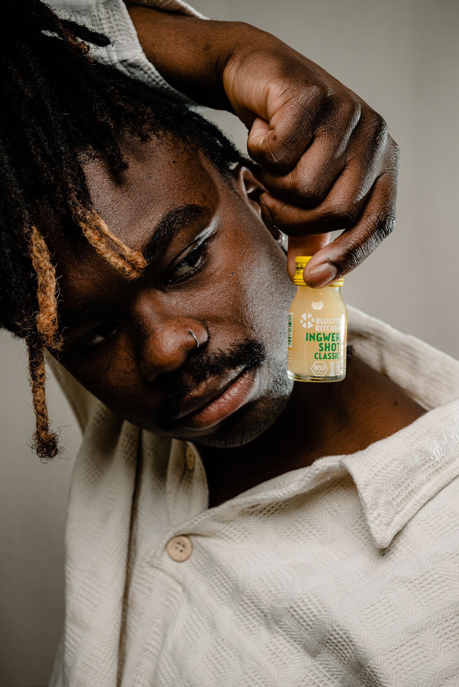 a man with dreadlocks holding a klosterkitchen shot bottle 