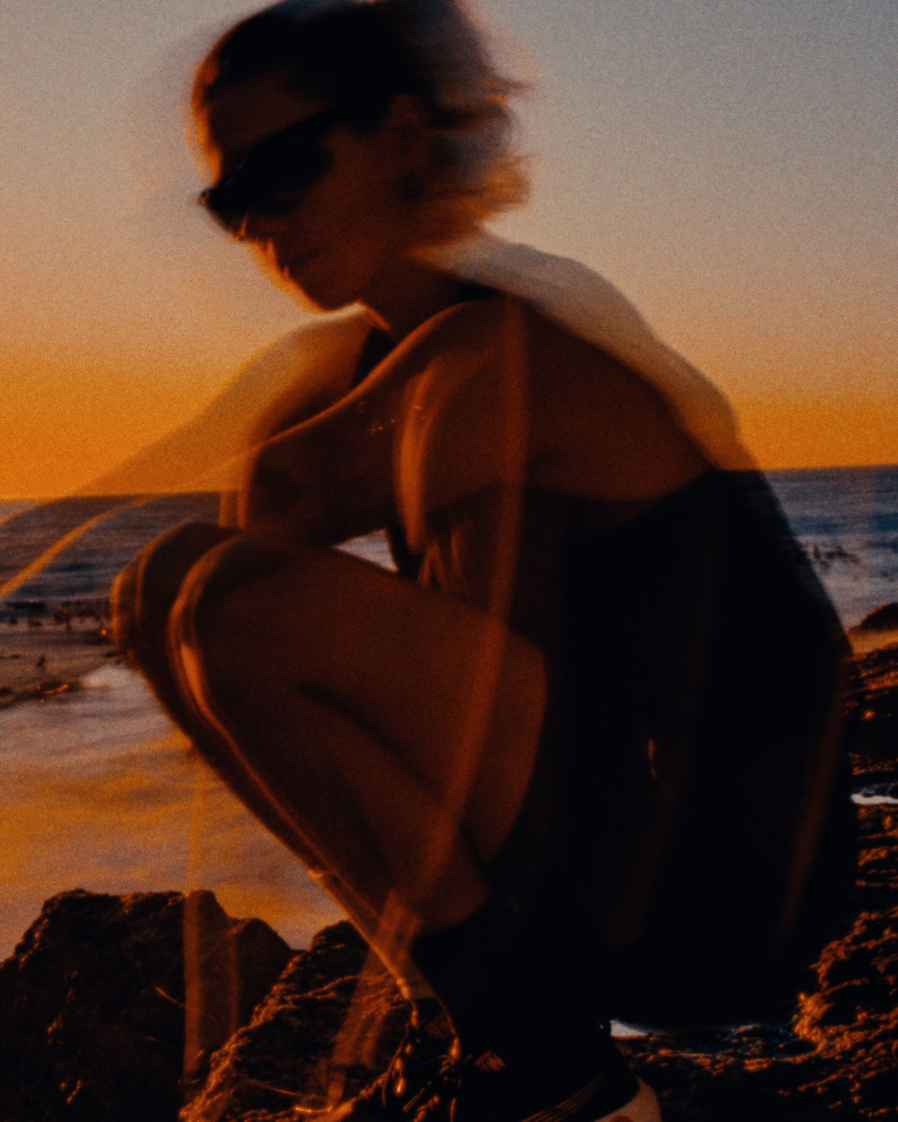 a blurry image of a person crouching on a rock