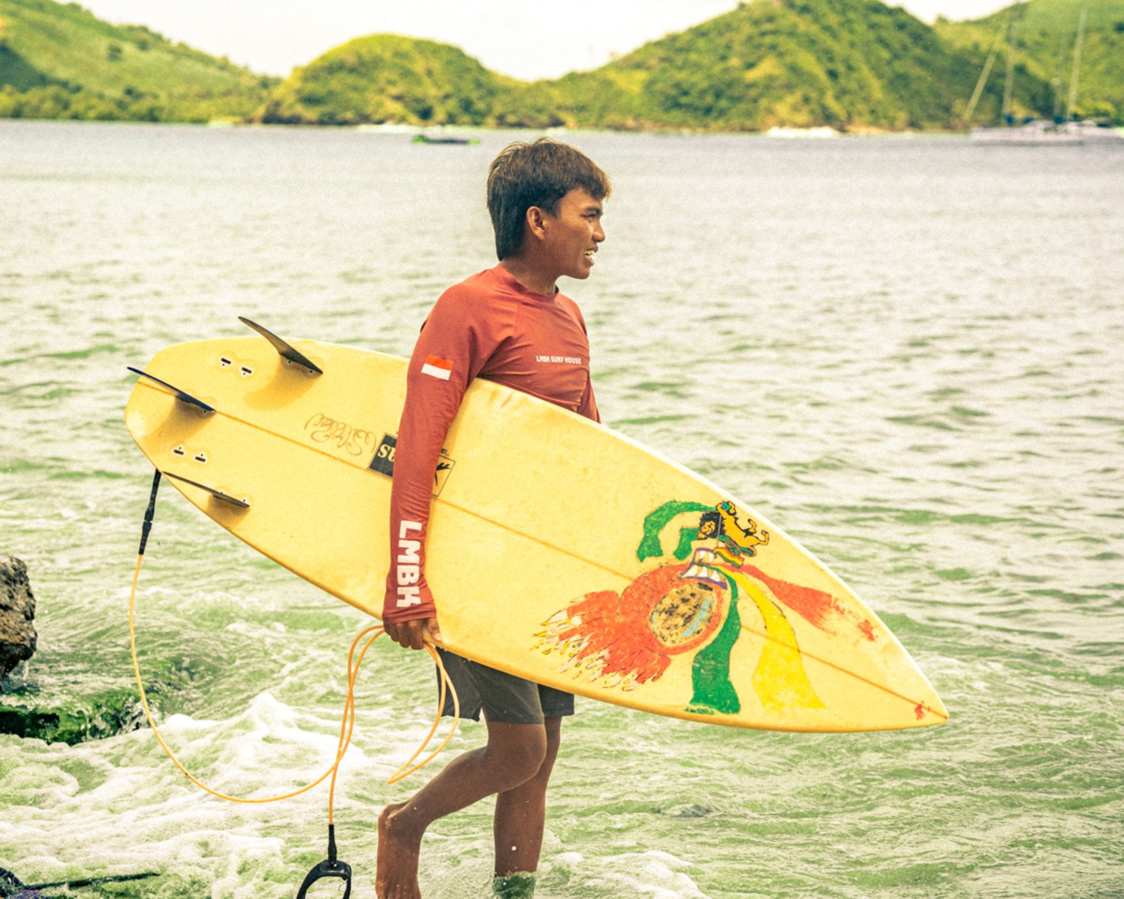 An LMBK surf coach scouting the reef at Gerupuk, board in hand, ready for the morning session.